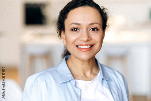 Close-up portrait of beautiful joyful successful mature mixed race brunette woman, dressed in stylish shirt, employee or lawyer, looking at camera, smiling friendly