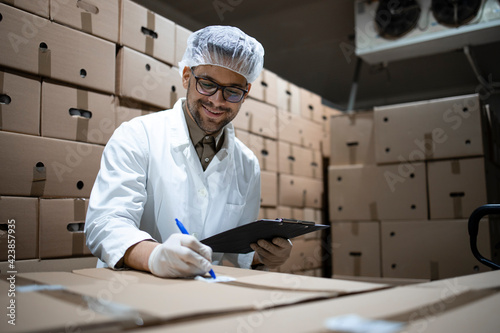 Canvastavla Factory worker wearing hairnet and hygienic gloves preparing fresh food packages for distribution and market sale