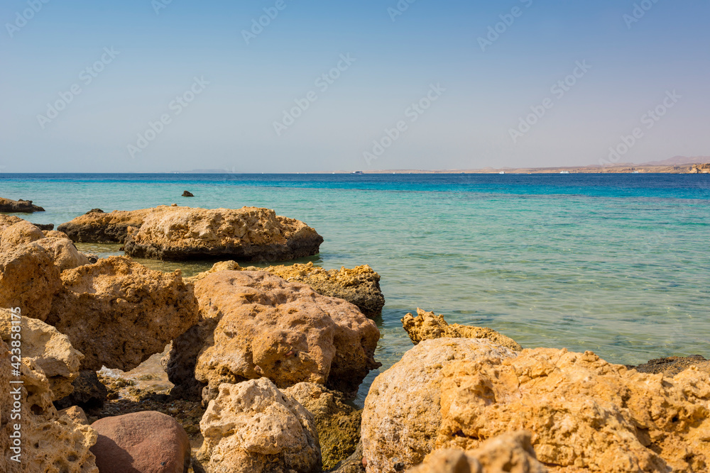 sunny landscape of the Red Sea coast in Sharm El Sheikh, Hadaba, with blue-turquoise water and orange-yellow-black stones