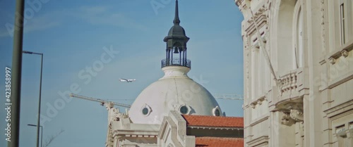 Plane is flying above an old church in the city of Lisbon, Portugal on a sunny day. Slow motion.