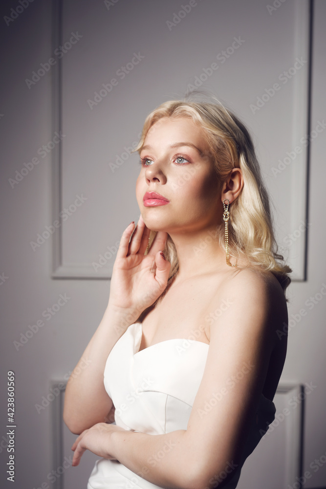 Beautiful bride portrait. A woman in a wedding dress with makeup and hairstyle in beautiful silver earrings. Wedding concept, beauty salon, wedding dress salon. Pensive girl.