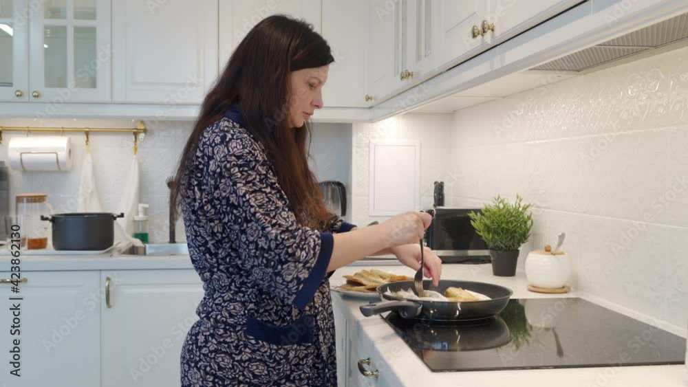 Woman cooking dinner frying Smelt koryushka fish in a frying pan in modern kitchen at home, koryushka rolled in wheat flour and gently fried. High quality 4k footage Woman cooking dinner frying Smelt koryushka fish in a frying pan in modern kitchen at home, koryushka rolled in wheat flour and gently fried. High quality 4k footage