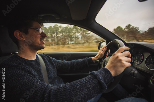 Happy guy sitting driving a car with two hands on the steering wheel © cesc92