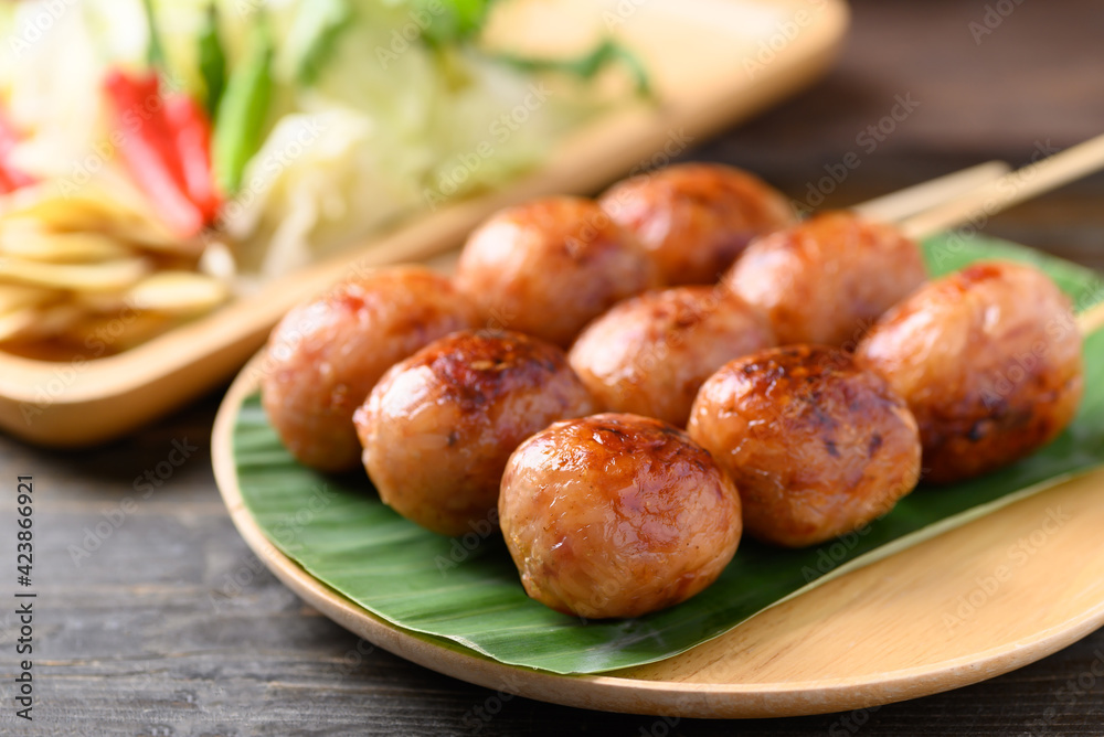 Thai sausage or Isan sausage (grilled fermented rice with minced pork) eating with fresh cabbage, ginger, and chili peppers Thai sausage or Isan sausage (grilled fermented rice with minced pork) eating with fresh cabbage, ginger, and chili peppers