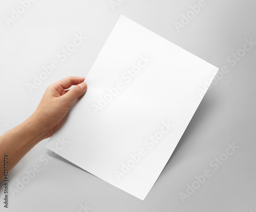 Hand holding a blank a4 size paper isolated on grey background. photo