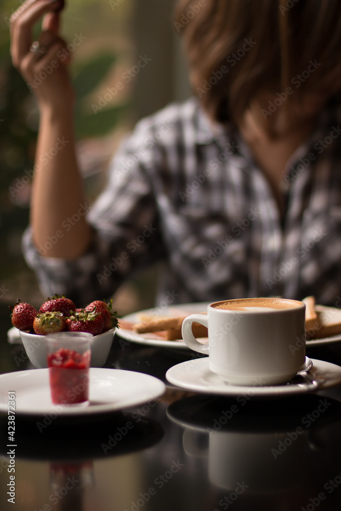 Table with breakfast in restaurant with fresh strawberries, coffee, toast
