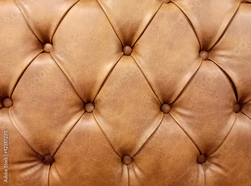 Vintage brown leather Sofa Button for textured background, Closeup. Genuine leather upholstery background with copyspace for a luxury decoration in Brown tones.