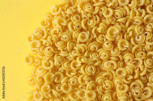 Pasta in the form of a flying saucer on a yellow background. Concept - Italian cuisine. Free space for text.