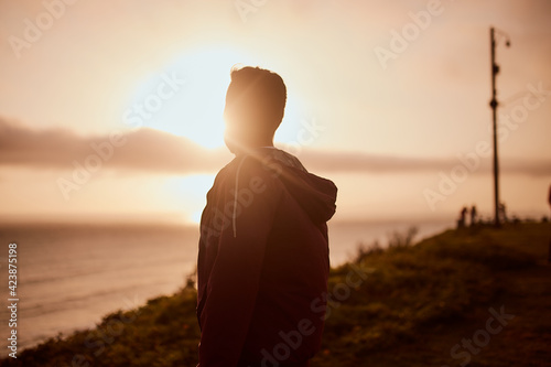 Hombre joven descansa en un parque durante un atardecer de verano. Hombre mirando al horizonte del mar. 