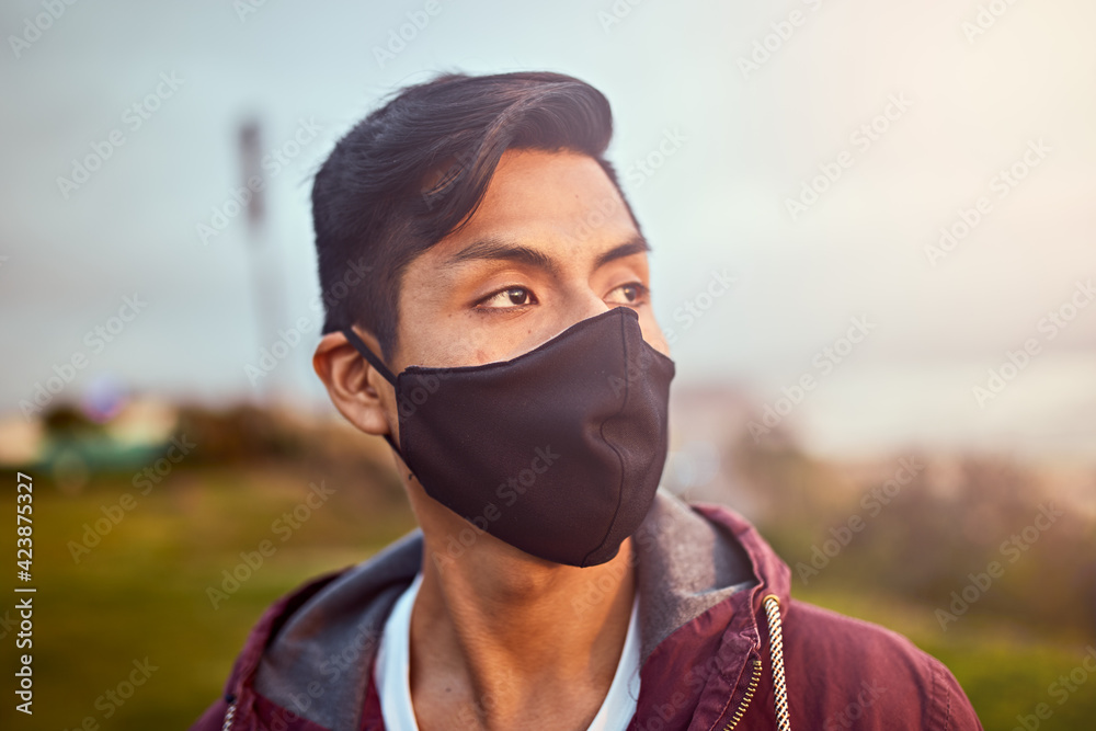 Hombre joven descansa en un parque durante un atardecer de verano. Hombre mirando al horizonte del mar con una mascarilla. Hombre joven descansa en un parque durante un atardecer de verano. Hombre mirando al horizonte del mar con una mascarilla.