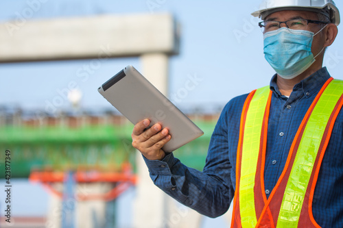Asian man Senior Engineer expert professional use tablet work on site construction, Then man wera face mask protect coronavirus covid19 ,PM2.5