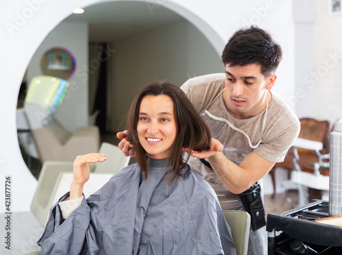 Young woman at beauty salon choosing hair treatment with male hairdresser