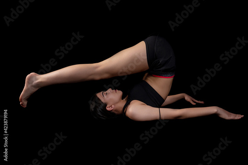 Young woman doing fitness exercise training isolated on the black background. Horizontal shot.