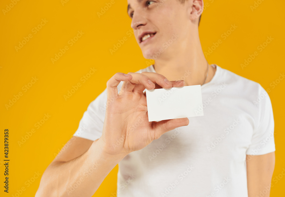 man in white t-shirt showing business card on yellow background cropped view man in white t-shirt showing business card on yellow background cropped view