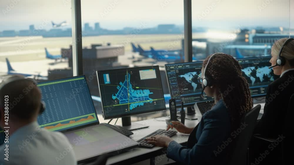 Female Air Traffic Controller with Headset Talk on a Call in Airport Tower. Office Room is Full of Desktop Computer Displays with Navigation Screens, Airplane Flight Radar Data for the Team. Female Air Traffic Controller with Headset Talk on a Call in Airport Tower. Office Room is Full of Desktop Computer Displays with Navigation Screens, Airplane Flight Radar Data for the Team.