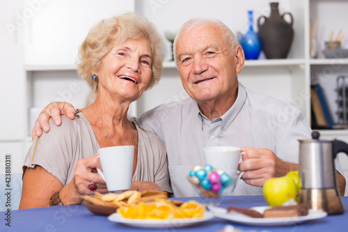 Portrait of happy mature couple having good time drinking tea in kitchen.