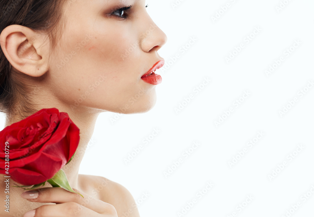 Side view of romantic woman with red flower near face Side view of romantic woman with red flower near face
