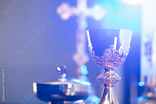 Religion theme – Easter. Catholic symbols composition. The Cross, monstrance and golden chalice on blue background. 