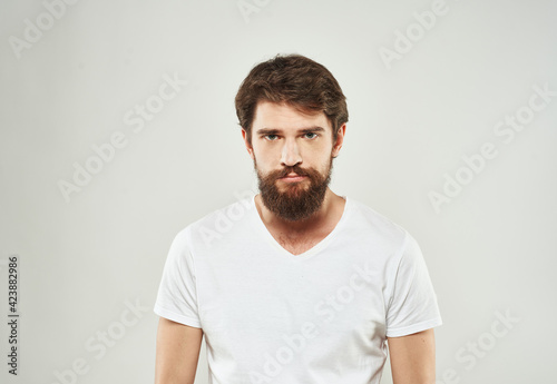 Bearded man in white T-shirt puzzled look sad face cropped look © SHOTPRIME STUDIO