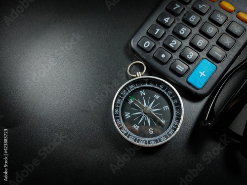 Selective focus of calculator,glasses and compass on black background with copy space.