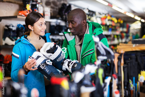 young couple choosing new comfortable ski boots in ski equipment shop
