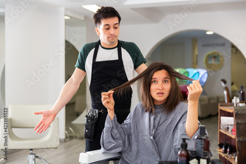 Portrait of shocked woman displeased with new haircut and regretting hairdresser in modern hairsalon
