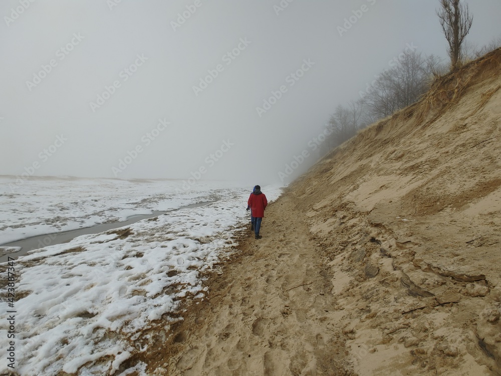 A man stands on the beach of a frozen lake michiagn