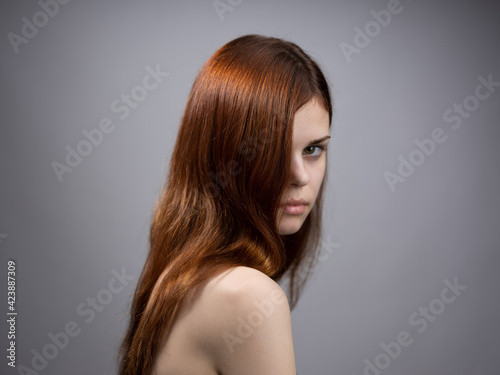 Beautiful woman with loose red hair on a gray background bared shoulders portrait