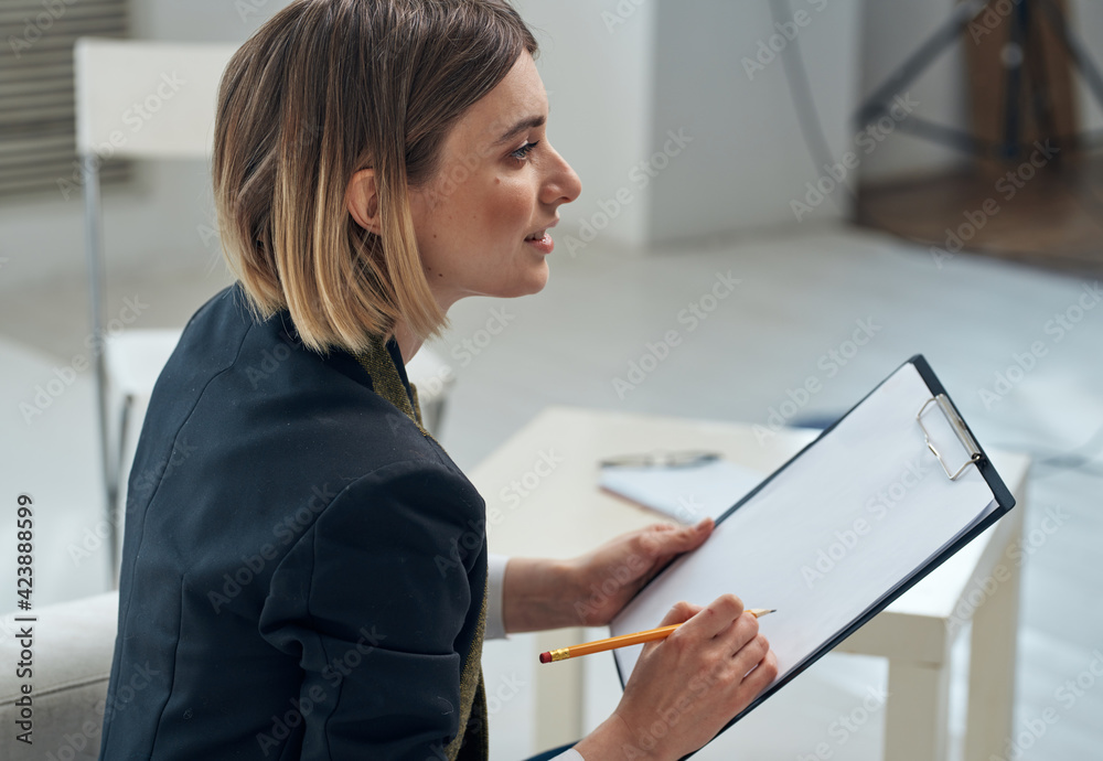 Side view of a business woman with documents sits indoors Side view of a business woman with documents sits indoors