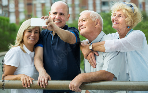 Company of smiling mature people taking selfie in park outdoor