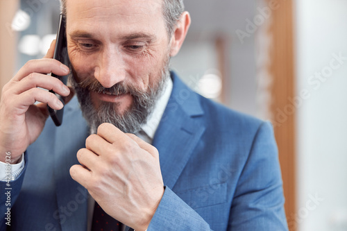 Happy adult caucasian businessman using smarthopne in a modern stylish office