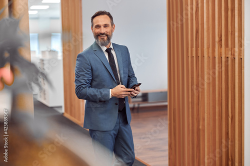 Happy adult caucasian businessman using smarthopne in a modern stylish office