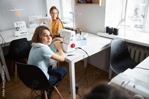 Adorable girls sewing clothes in dressmaking studio