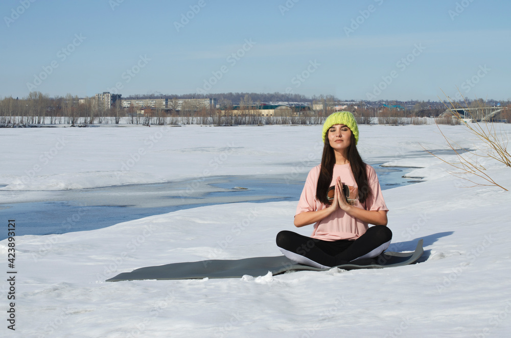 Fototapeta premium yoga in nature. girl meditates in winter on the river bank