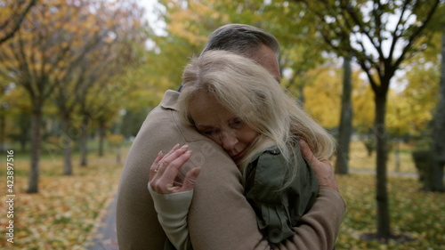 Medium shot of married couple hugging gently in autumn park. Happy lovers .