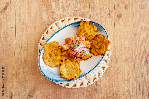 a plate of fried plantain served with shredded beef drizzled with onion and lime dressing from above central
