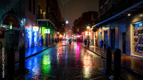 Bourbon Street in new orleans is rain soaked after a heavy spring downpour. Colored lights reflect off the famous street. 