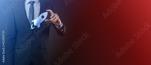 Startup business concept  Businessman holding tablet and icon rocket is launching and soar flying out from screen with network connection on dark background.