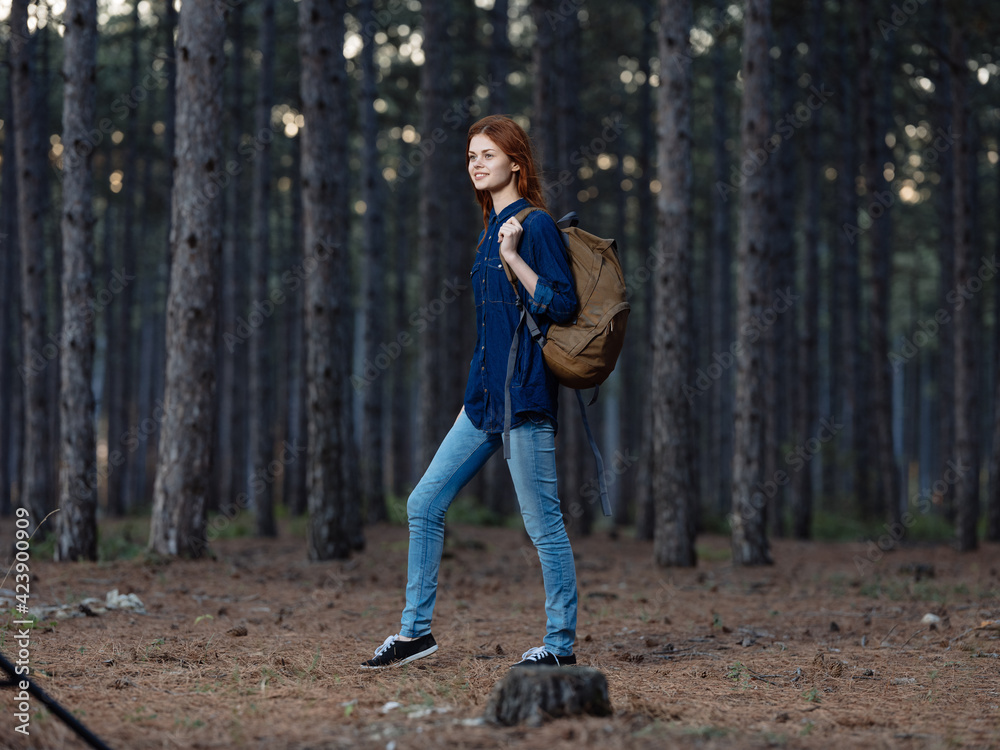 Woman Tourist in full growth in a pine forest with a backpack on her back
