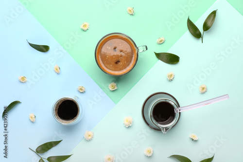Tasty coffee with spring flowers on color background