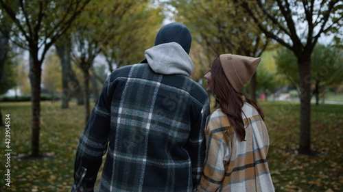 Back view of loving couple walking in autumn park in daytime. Close back view. © stockbusters