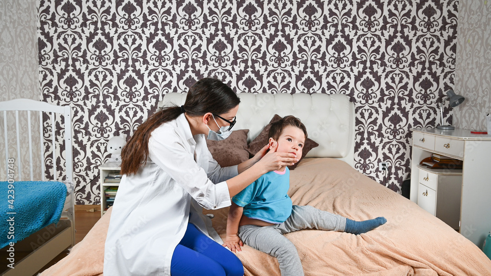 Obraz premium The doctor checks the child's ears at home