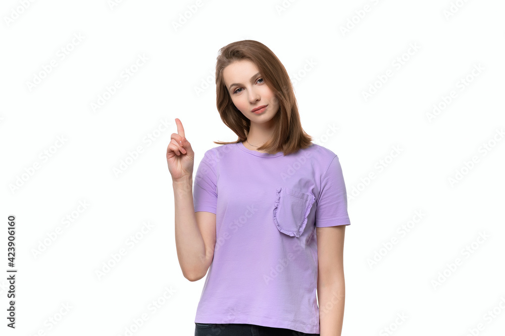 Serious young woman look at camera make warning sign. Girl raises finger up, says: Attention please Serious young woman look at camera make warning sign. Girl raises finger up, says: Attention please