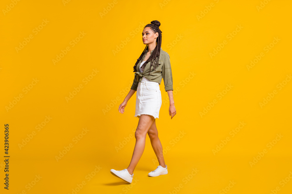 Photo portrait full body profile side view of woman walking isolated on vivid yellow colored background Photo portrait full body profile side view of woman walking isolated on vivid yellow colored background