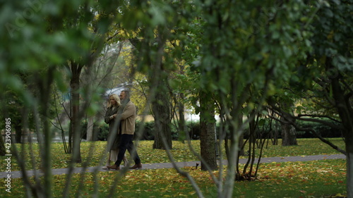 Wide shot of stylish mature couple having walking in autumn nature.