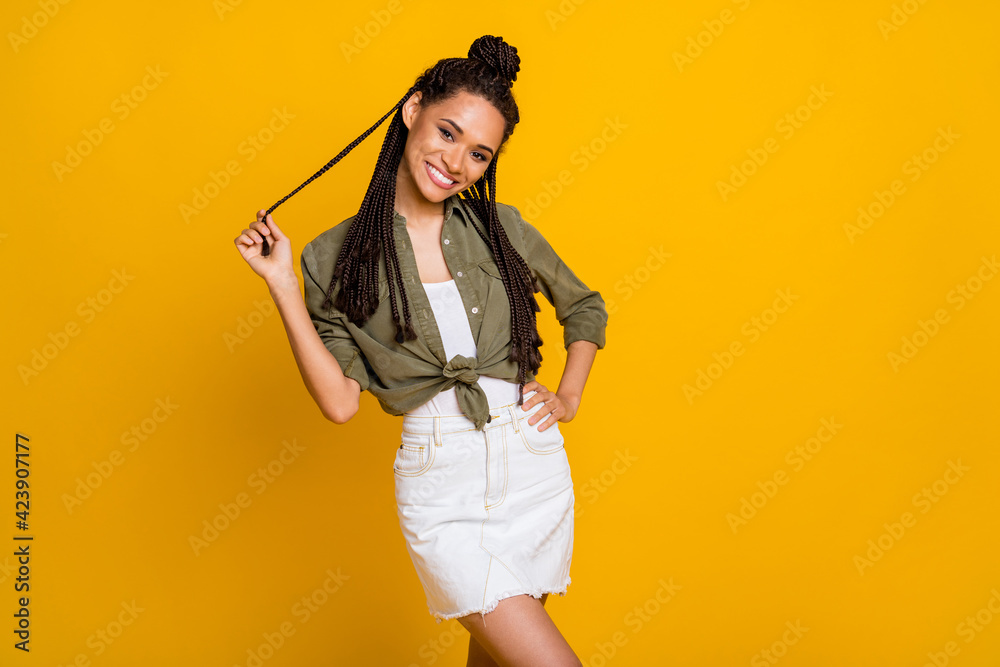 Photo portrait of woman playing with hair isolated on vivid yellow colored background Photo portrait of woman playing with hair isolated on vivid yellow colored background