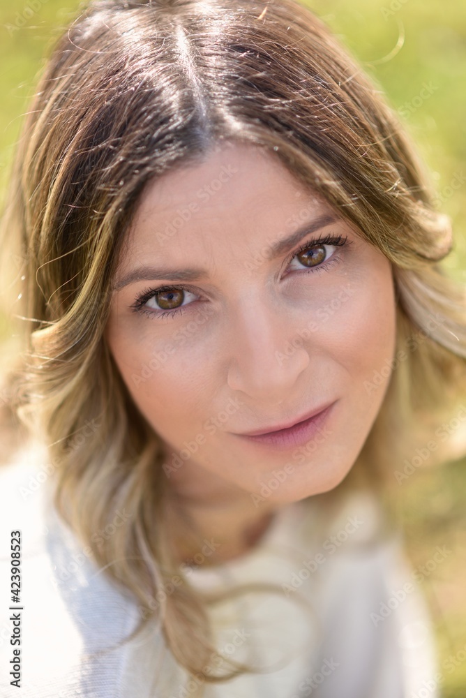 Ritratto all'aperto di una donna dai capelli biondi.