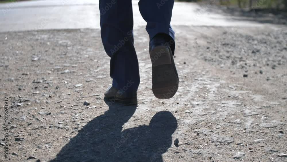 Looking on the feet of man, in classic shoes and trousers, walking from off-road to new asphalt way. Metaphor of going to the good changes Looking on the feet of man, in classic shoes and trousers, walking from off-road to new asphalt way. Metaphor of going to the good changes