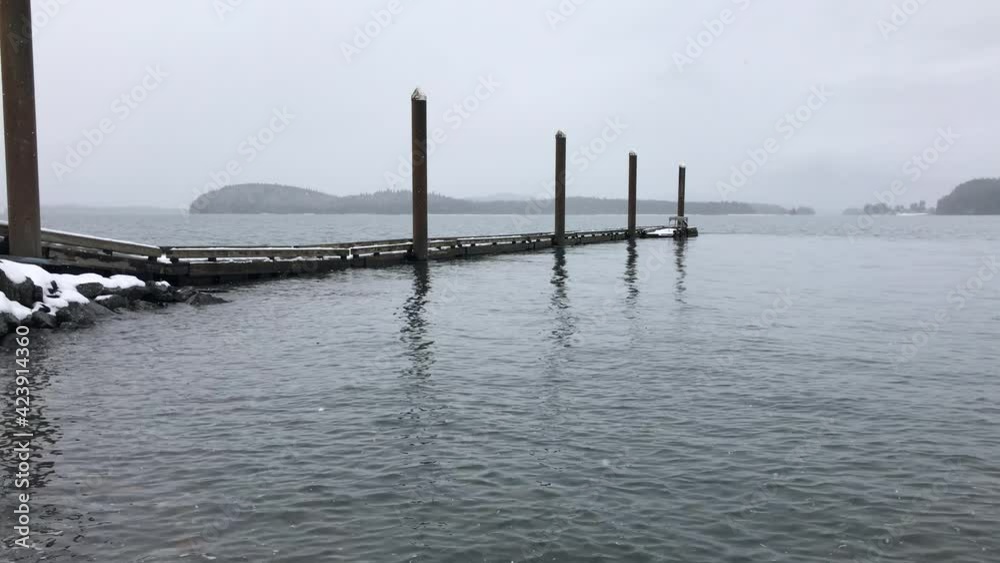 Snowing boat dock surrounded by lapping tide ocean in Alaska. Snowing boat dock surrounded by lapping tide ocean in Alaska.