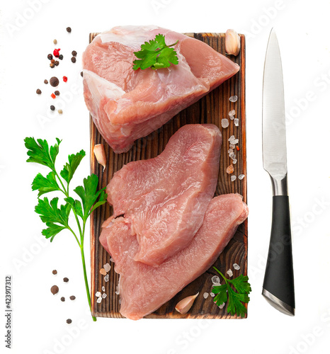 Fresh turkey fillet. Cut into pieces. On a wooden board. Garnished with herbs and spices. White background. Isolated. Close-up. View from above.